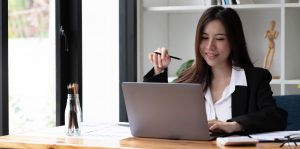 Business asian woman using laptop for do math finance on wooden desk in office, tax, accounting